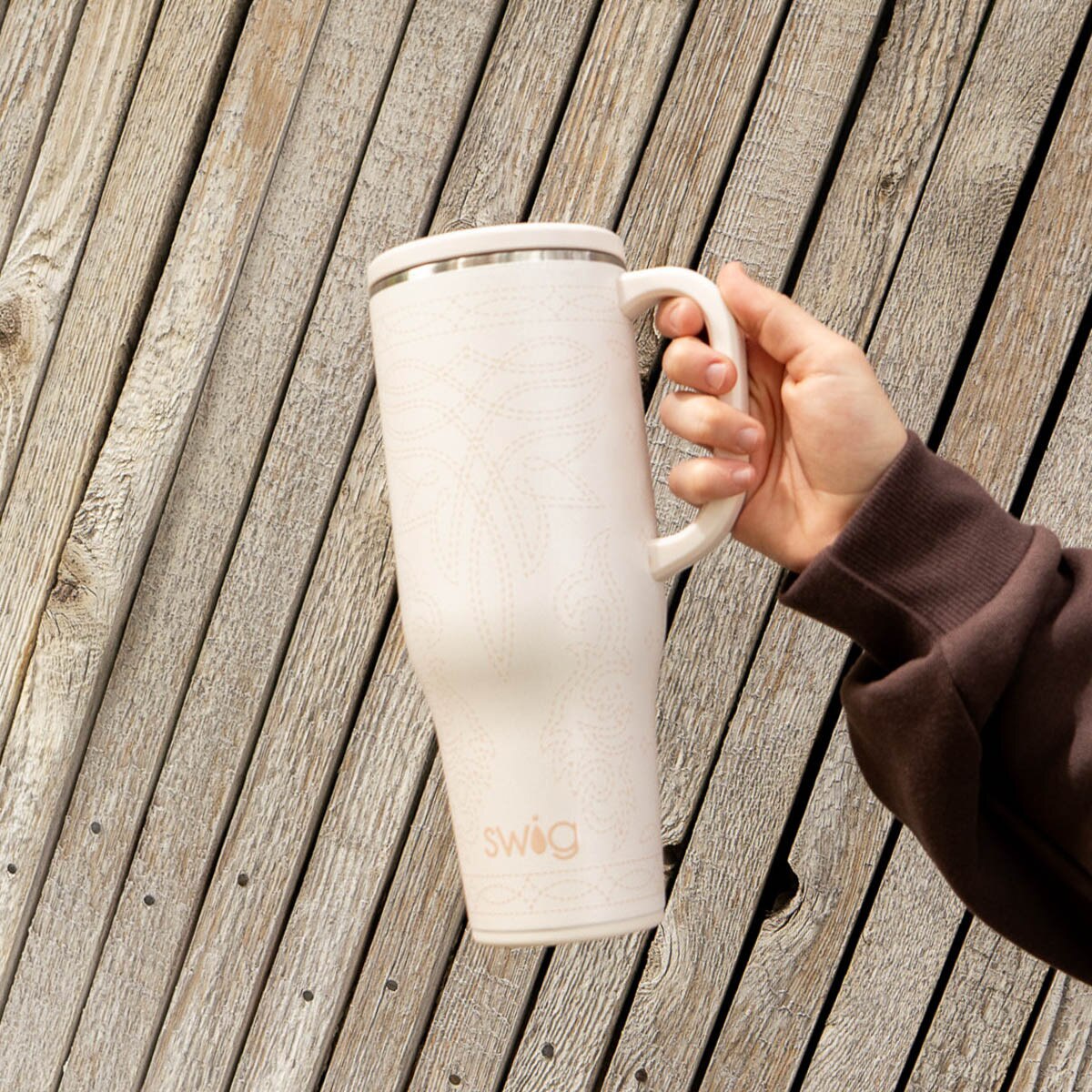 Hand holding cream saddle stitch swig life to go 40oz tumbler